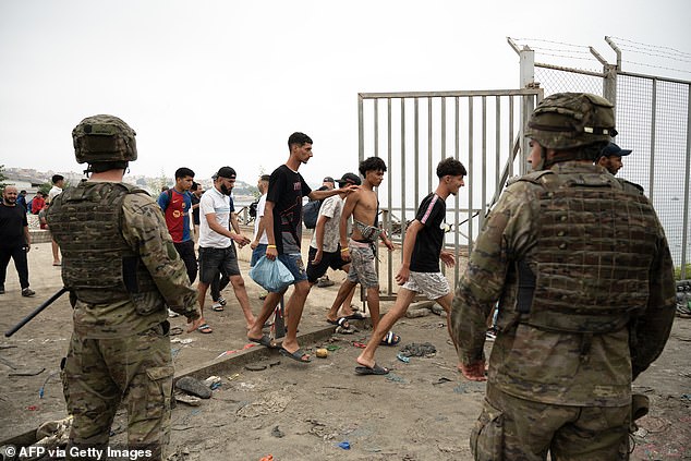 Migrants cross back to Morocco after they crossed into Cueta under the supervision of Spanish army soldiers