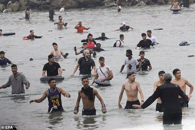 A group of migrants wade through the water near the Tarajal border crossing in Ceuta